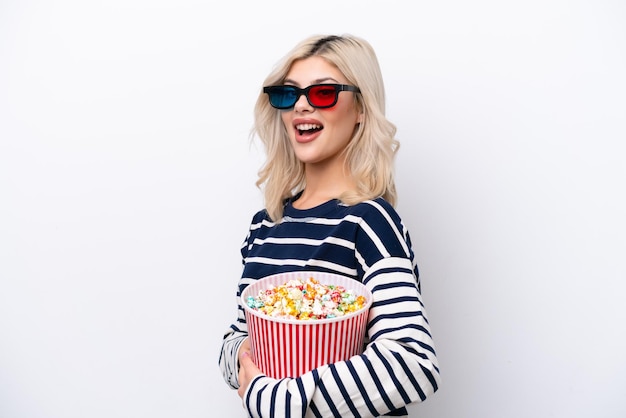 Young Russian woman isolated on white background with 3d glasses and holding a big bucket of popcorns