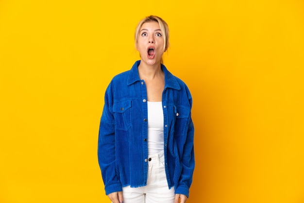 Young russian woman isolated on yellow background looking up and with surprised expression