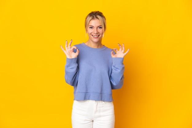 Young Russian woman isolated on yellow background showing ok sign with two hands