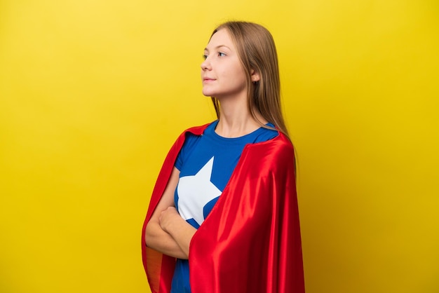 Young Russian woman isolated on yellow background in superhero costume with arms crossed