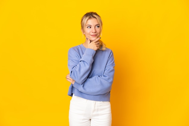 Young russian woman isolated on yellow background thinking an idea while looking up
