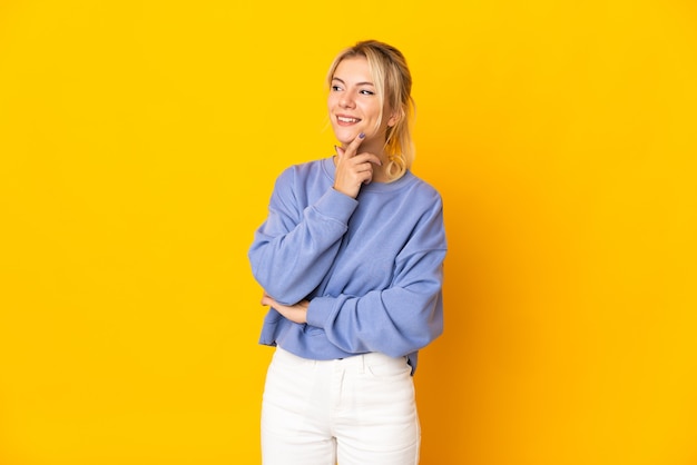 Young Russian woman isolated on yellow background thinking an idea while looking up