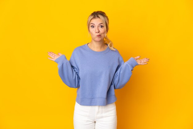 Young Russian woman isolated on yellow having doubts while raising hands