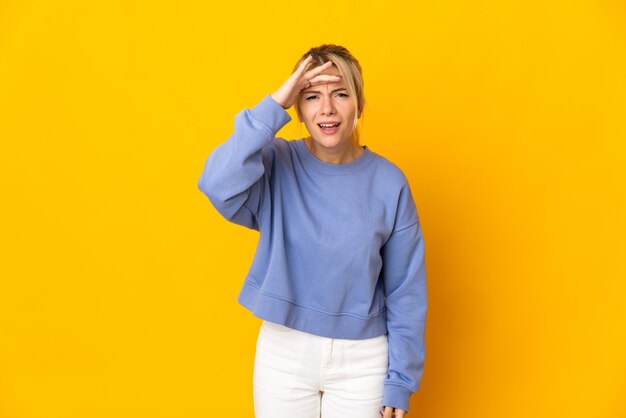 Young russian woman isolated on yellow wall looking far away with hand to look something