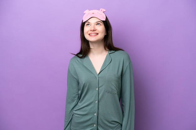 Photo young russian woman in pajamas isolated on purple background thinking an idea while looking up