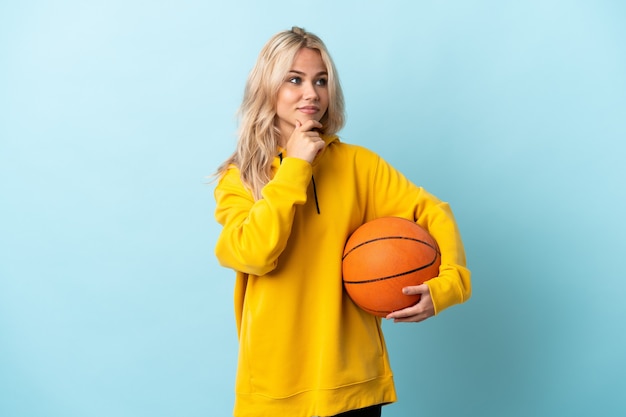 Young Russian woman playing basketball isolated on blue thinking an idea while looking up