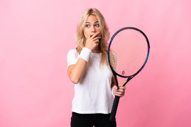 Young Russian woman playing tennis isolated on purple wall doing surprise gesture while looking to the side