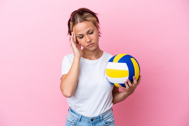 Молодая русская женщина играет в волейбол на розовом фоне с головной болью