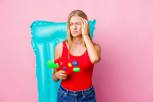 Young russian woman playing with a water gun with an air mattress