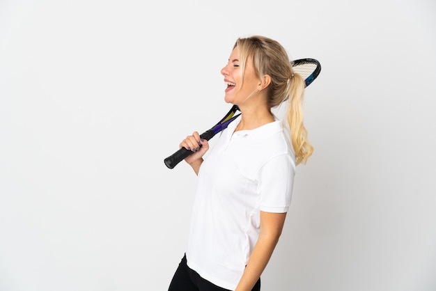 Young Russian woman tennis player isolated on white wall laughing in lateral position