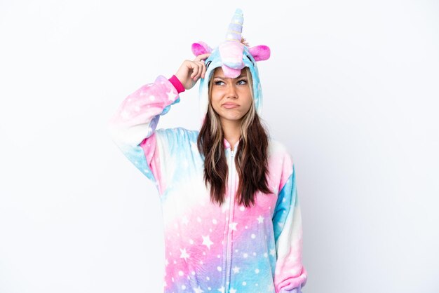 Young Russian woman wearing a unicorn pajama isolated on white background having doubts and with confuse face expression