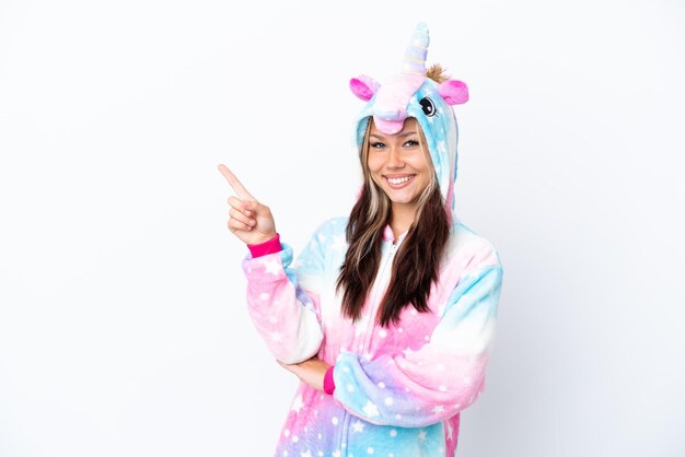 Young Russian woman wearing a unicorn pajama isolated on white background pointing finger to the side