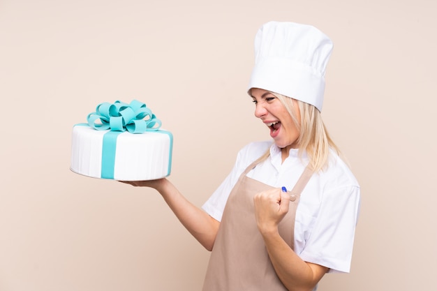 Young Russian woman with a big cake over isolated wall celebrating a victory