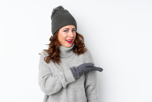 Young Russian woman with winter hat over isolated  extending hands to the side for inviting to come