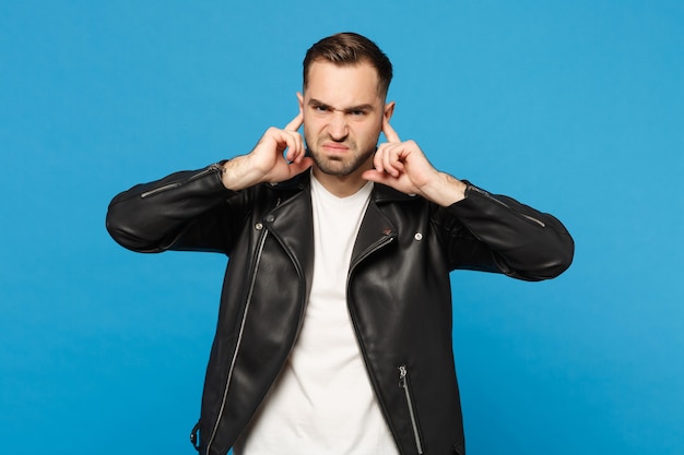 Young sad frustrated worried unshaven man in black jacket white t-shirt looking camera isolated on blue wall background studio portrait. People sincere emotions lifestyle concept. Mock up copy space.