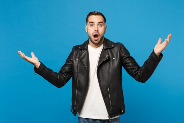 Young sad frustrated worried unshaven man in black jacket white t-shirt looking camera isolated on blue wall background studio portrait. People sincere emotions lifestyle concept. Mock up copy space.