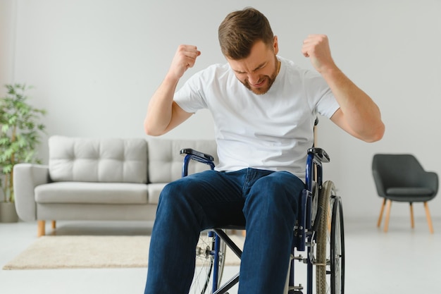 Young sad man in a wheelchair at home