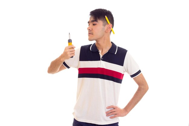 Young sad man with black hair with pencil behind his ear holding yellow screwdriver