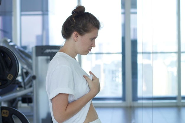 若い悲しい動揺した女性は、イライラして鏡を見て太ったお腹のせいで失望しています