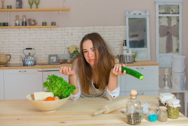 キッチンの美しいインテリアに座って健康的な食べ物を食べる若い悲しい女性。ファーストフードと健康食品の選択