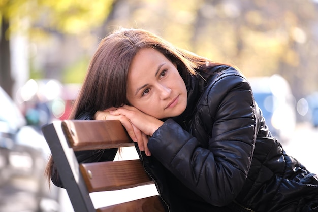 Giovane donna triste seduta da sola sulla panchina di strada all'aperto pensando a qualcosa la solitudine e la depressione durante il periodo difficile nel concetto di vita