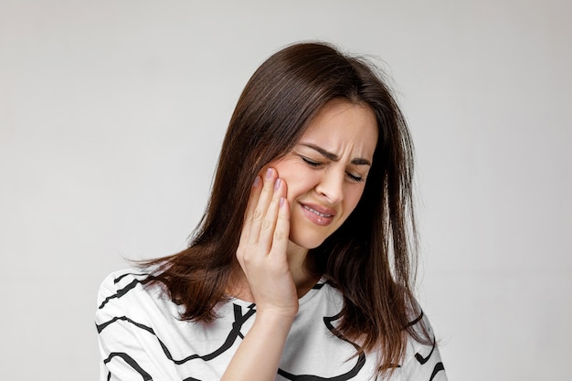 Young sad woman suffering from tooth pain