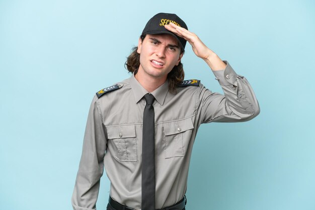 Young safeguard man isolated on blue background looking far away with hand to look something