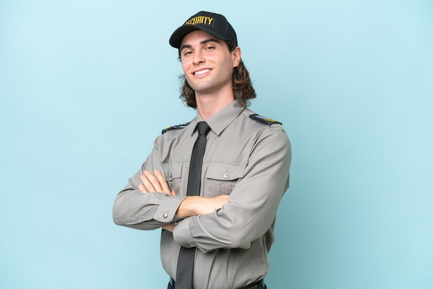 Young safeguard man isolated on blue background with arms crossed and looking forward