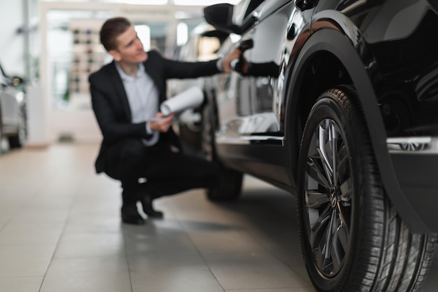 Young sales manager taking notes while checking new automobile at luxury car salon selective focus