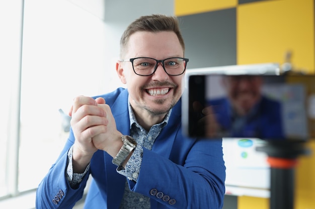 Young satisfied male business coach clenching his hands into fist in front of mobile phone