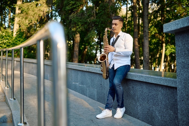 Young saxophonist plays the saxophone in park