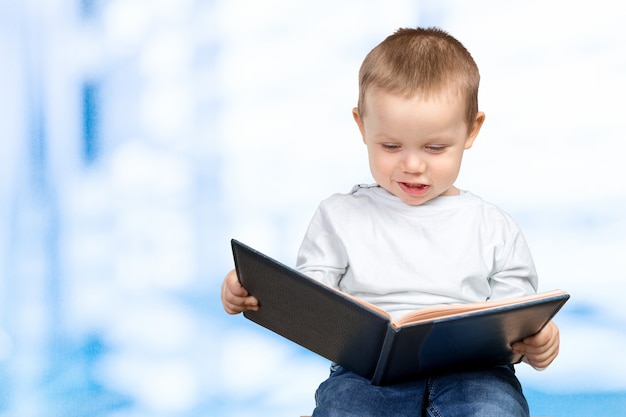 A young school boy is holding a blue book