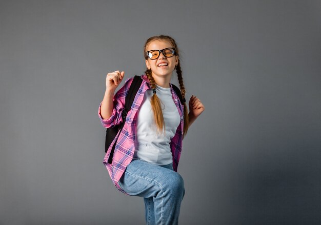 Young schoolgirl happy positive with smile rejoices in victory fists hands isolated on gray background