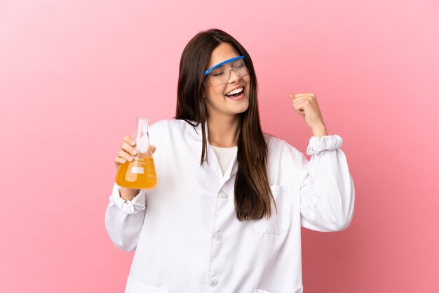 Young scientific girl over isolated pink background celebrating a victory