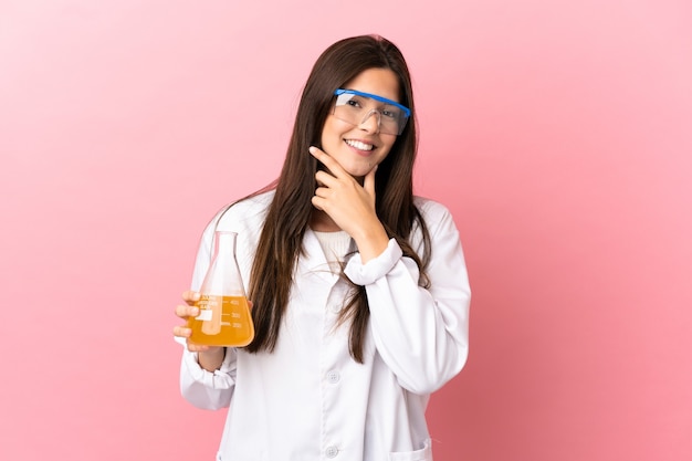 Young scientific girl over isolated pink background happy and smiling