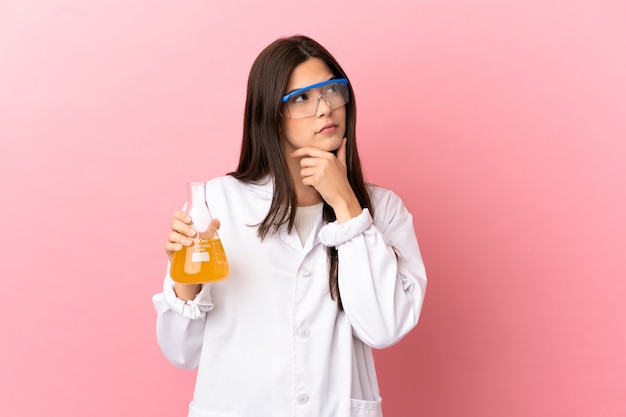 Young scientific girl over isolated pink background having doubts