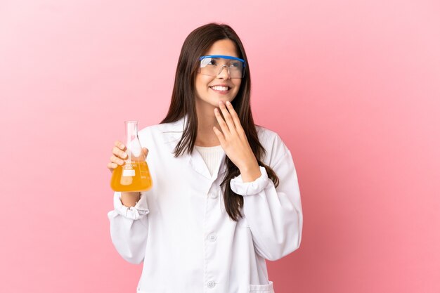 Young scientific girl over isolated pink background looking up while smiling