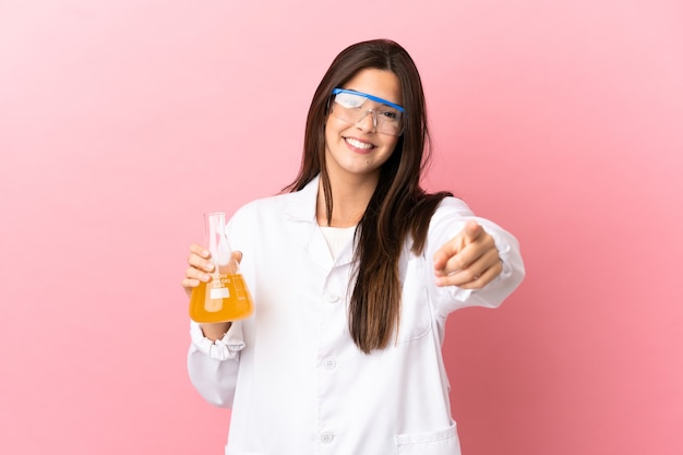 Young scientific girl over isolated pink background pointing front with happy expression