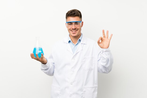 Колба лаборатории молодого научного холдинга показывая одобренный знак с пальцами
