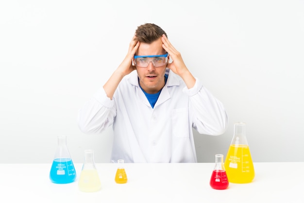 Young scientific with lots of laboratory flask with surprise facial expression