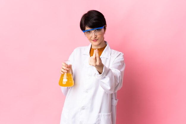 Young scientific woman isolated on pink background making money gesture