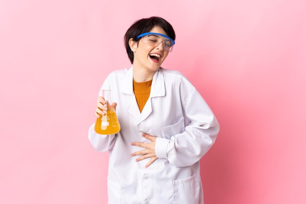 Young scientific woman isolated on pink space smiling a lot