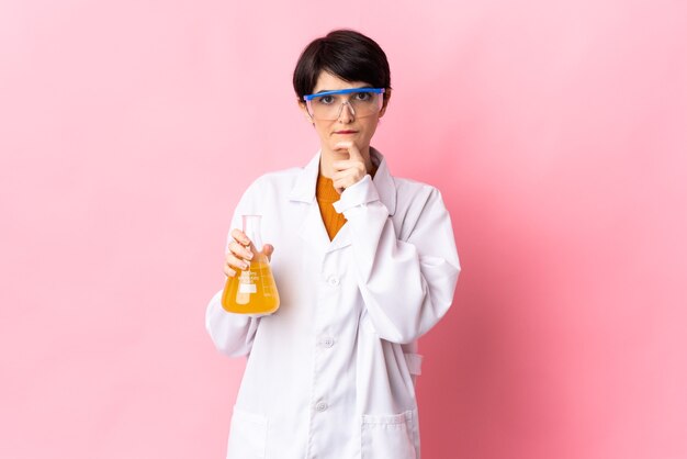 Young scientific woman isolated on pink wall having doubts and thinking