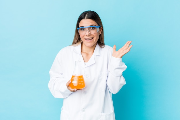 Young scientific woman receiving a pleasant surprise, excited and raising hands.