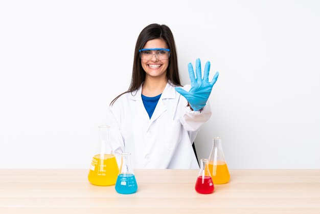 Young scientific woman in a table counting five with fingers