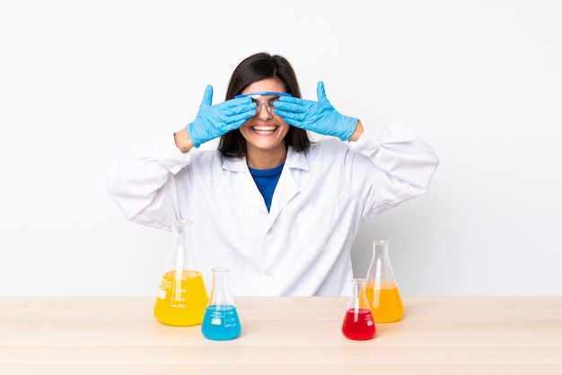 Young scientific woman in a table covering eyes by hands