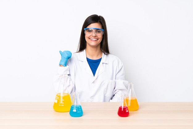 Young scientific woman in a table pointing to the side to present a product