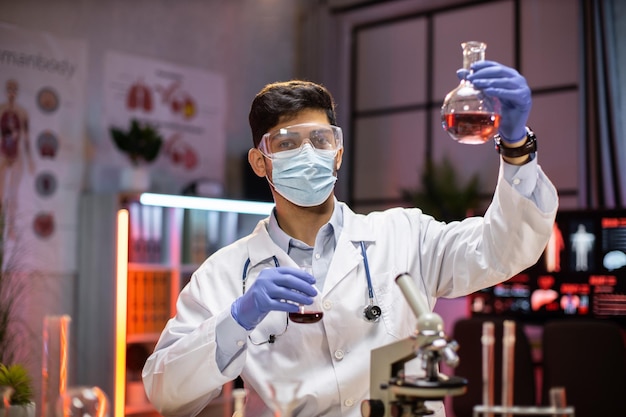 若い科学者アラブ人ラボ テクニカル サービス ラボ ガラス器具でフラスコを保持