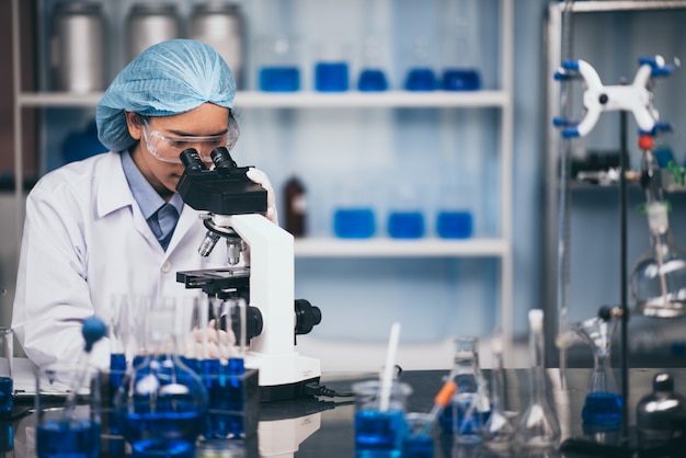 Young scientist looking through a microscope in a laboratory. Young scientist doing some research.