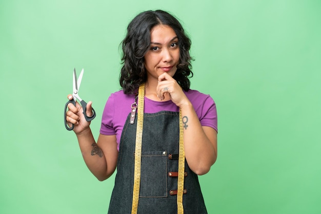 Young seamstress argentinian woman over isolated background thinking